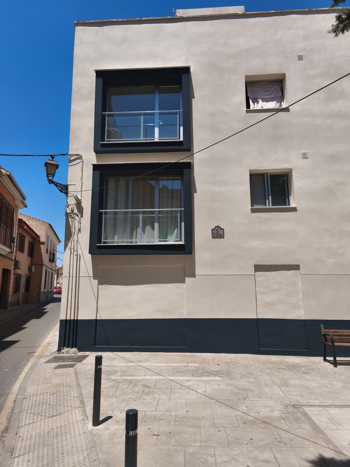 Fachada de comunidad pintada en crema con zócalo oscuro en Granada