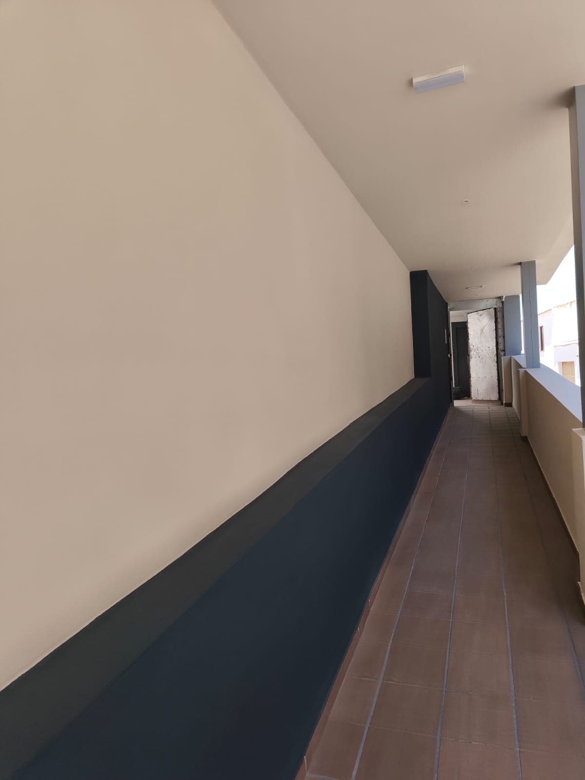 Pasillo de comunidad pintado en crema y azul oscuro en Granada
