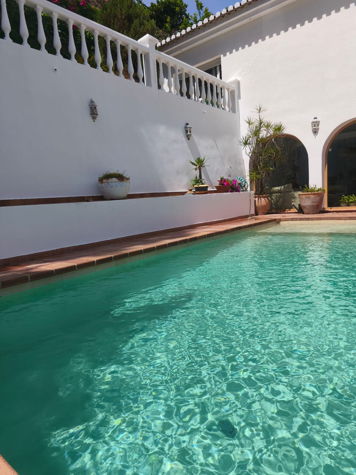 Pintura exterior en Granada: fachada blanca con piscina y arcos en vivienda unifamiliar