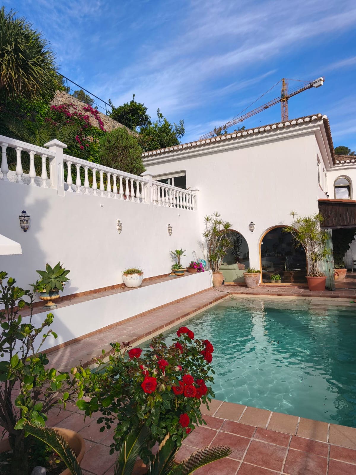 Pintura exterior en Granada: villa unifamiliar blanca con piscina y rosal rojo