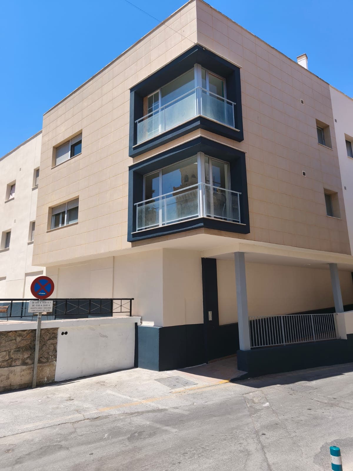 Pintura de comunidades en Granada: fachada renovada con zócalo azul marino y balcones acristalados