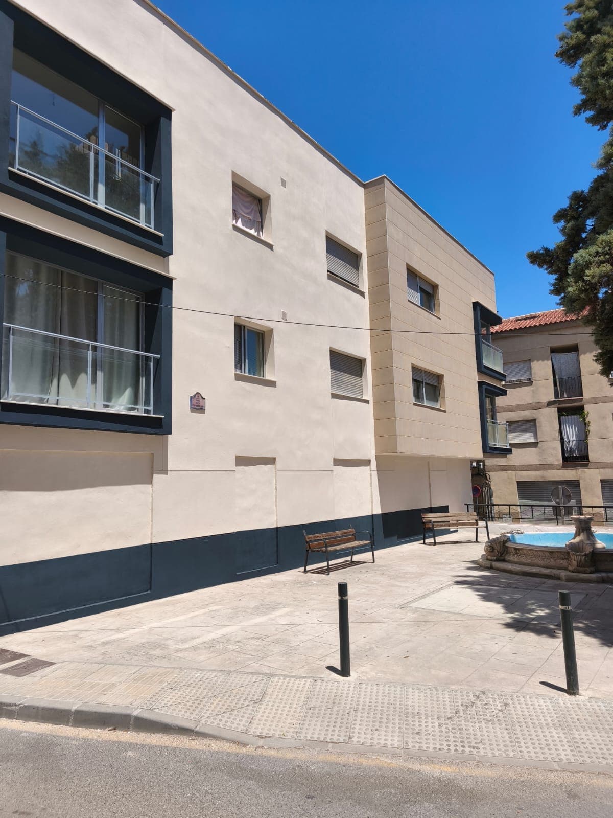Fachada lateral de comunidad de vecinos pintada en Granada con plazoleta enfrente